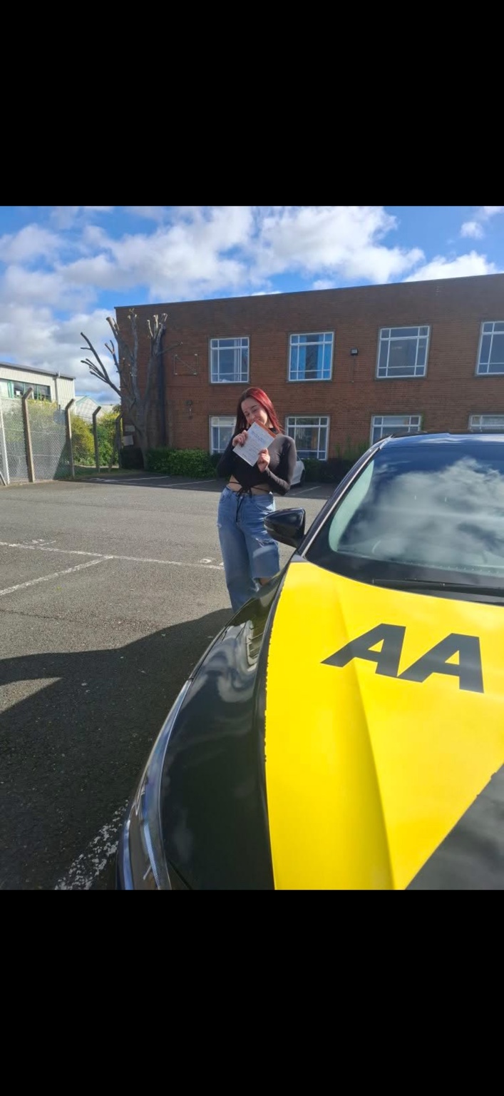 Learner celebrating a driving test pass beside a tuition car