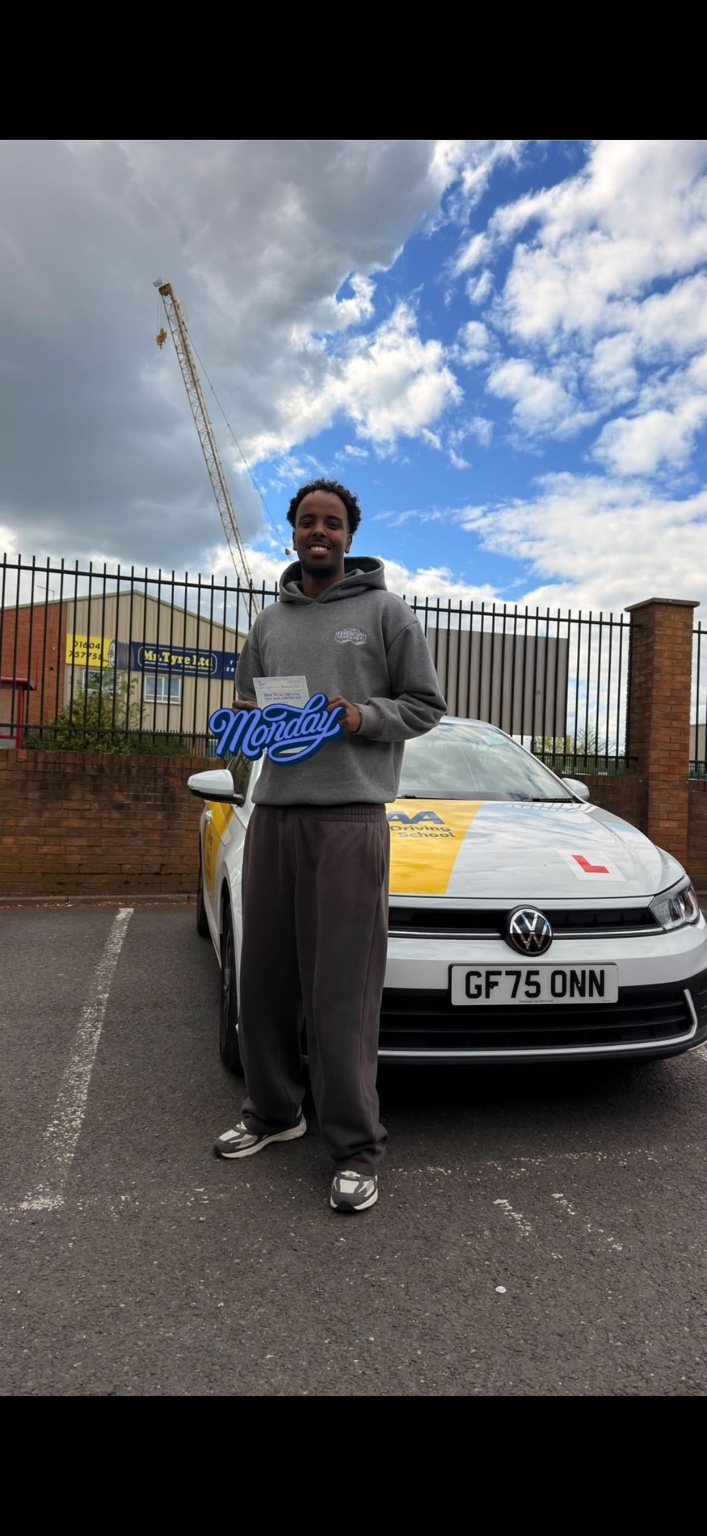 Learner holding a pass certificate beside a driving school car